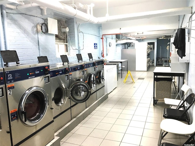 laundry area with washing machine and clothes dryer and light tile patterned floors