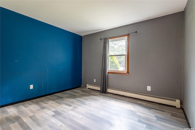 unfurnished room featuring light wood-type flooring and a baseboard heating unit