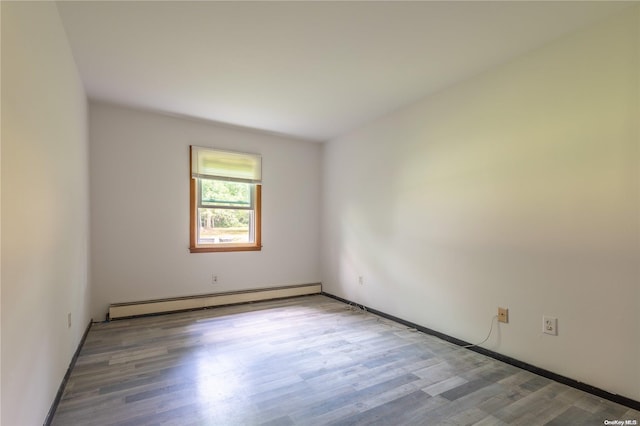 empty room featuring wood-type flooring and a baseboard radiator