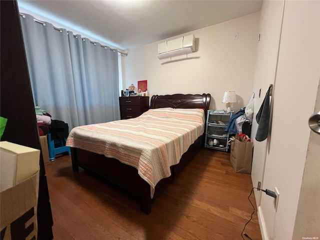 bedroom with a wall mounted AC and dark hardwood / wood-style flooring