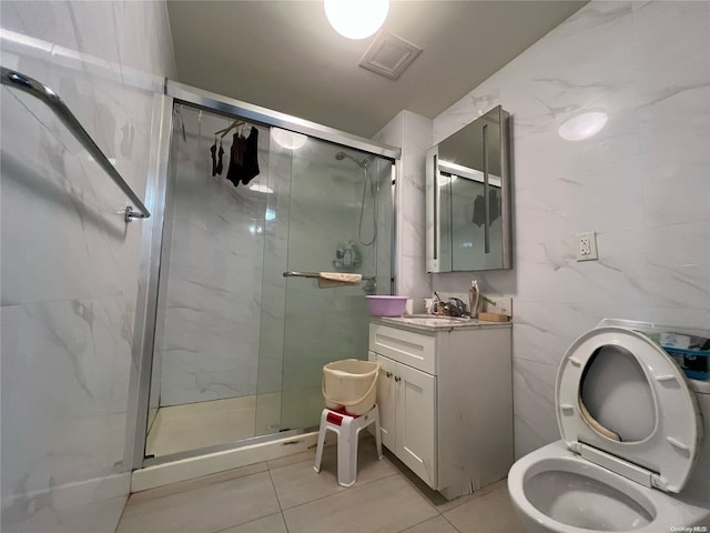 bathroom featuring vanity, tile walls, tile patterned flooring, toilet, and a shower with shower door