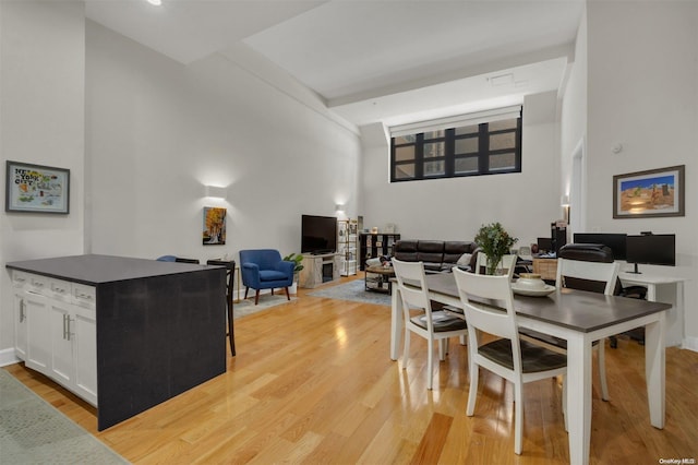 dining area with light hardwood / wood-style flooring and a high ceiling