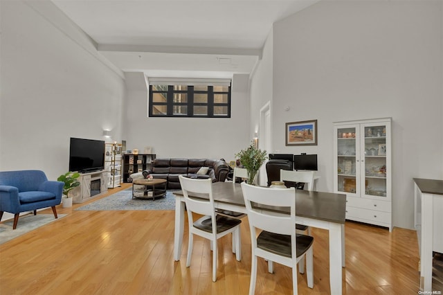 dining space featuring wood-type flooring and a high ceiling