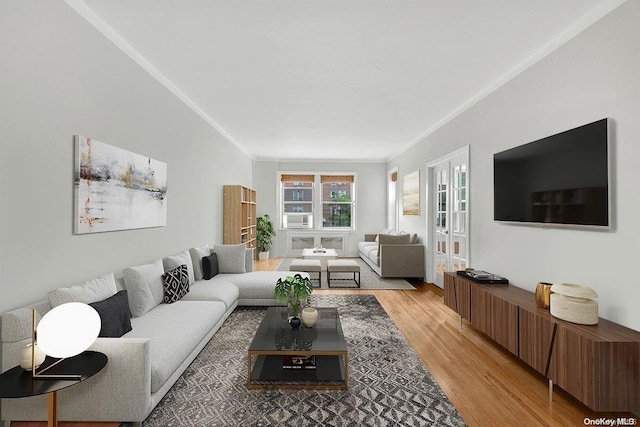 living room featuring french doors, cooling unit, ornamental molding, and light wood-type flooring