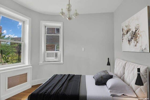 bedroom featuring multiple windows, cooling unit, a chandelier, and hardwood / wood-style flooring