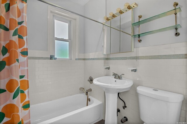 bathroom featuring shower / bath combo, tile walls, and toilet