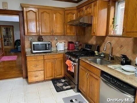 kitchen with stainless steel appliances, light stone counters, tasteful backsplash, and sink