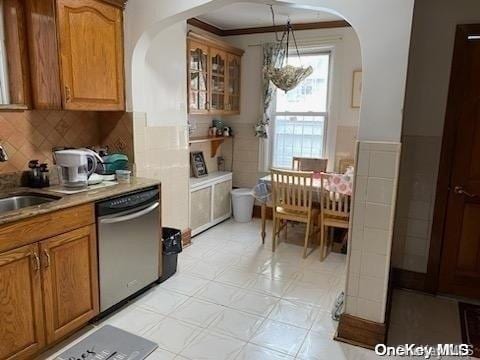 kitchen featuring dishwasher, hanging light fixtures, crown molding, and sink