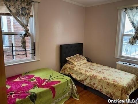 bedroom with hardwood / wood-style flooring, ornamental molding, and multiple windows