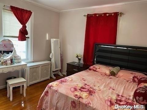 bedroom with wood-type flooring and ornamental molding