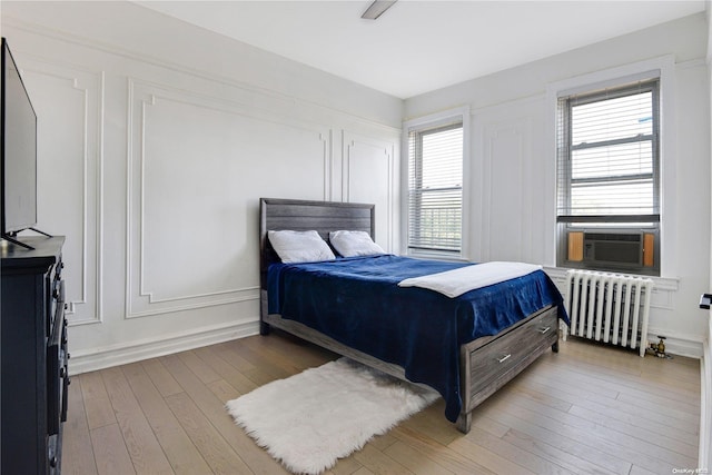 bedroom featuring hardwood / wood-style flooring, radiator, and cooling unit