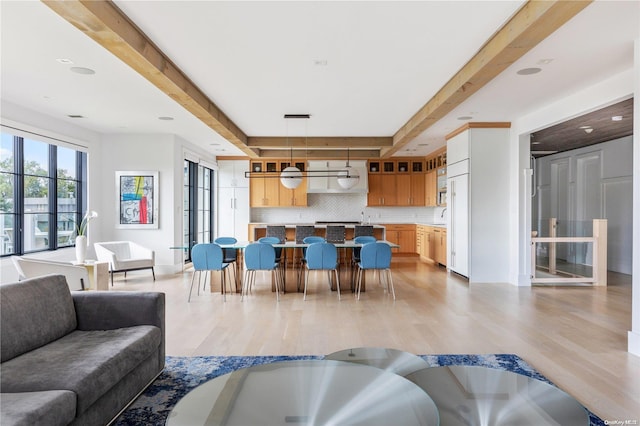 living room featuring beamed ceiling, light wood-type flooring, and a tray ceiling