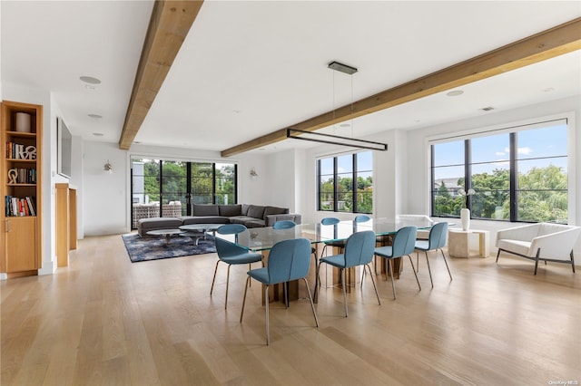 dining space with beam ceiling, light hardwood / wood-style flooring, and a healthy amount of sunlight