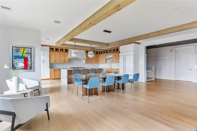 kitchen featuring beam ceiling, light hardwood / wood-style flooring, range hood, pendant lighting, and decorative backsplash