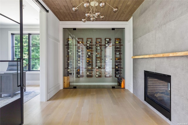 wine area with a notable chandelier, light hardwood / wood-style floors, wood ceiling, and a fireplace