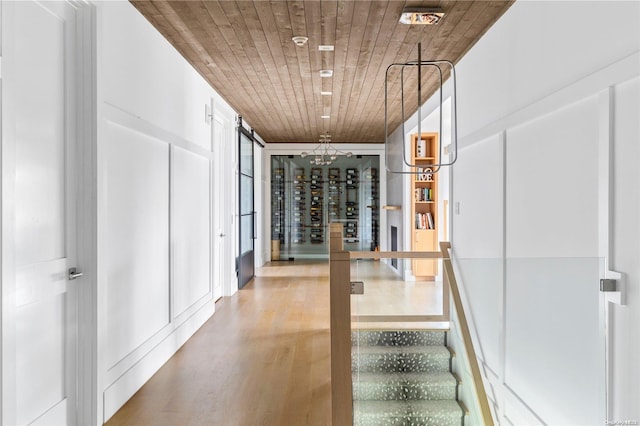 corridor with wood ceiling, a notable chandelier, and hardwood / wood-style flooring