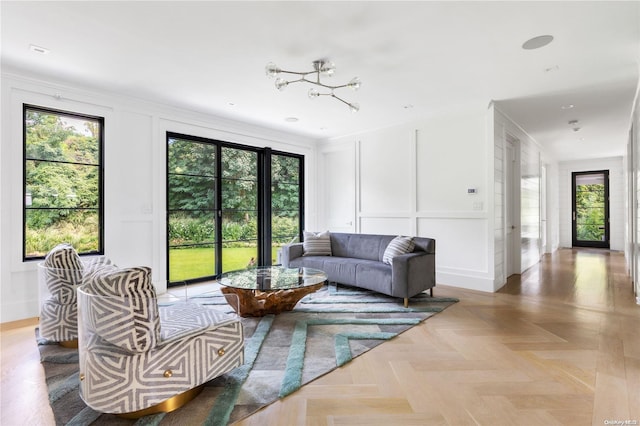 living room with light parquet floors, a chandelier, and ornamental molding