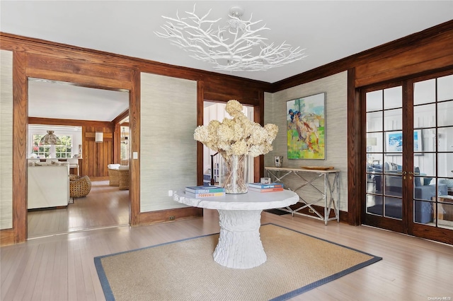 dining space featuring wood walls, french doors, wood-type flooring, and ornamental molding