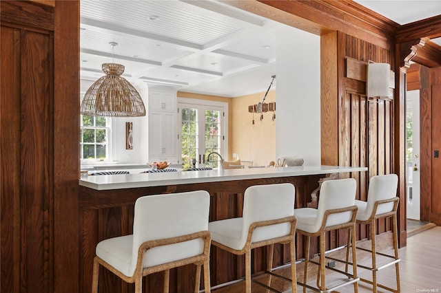 bar with beamed ceiling, light hardwood / wood-style floors, and coffered ceiling