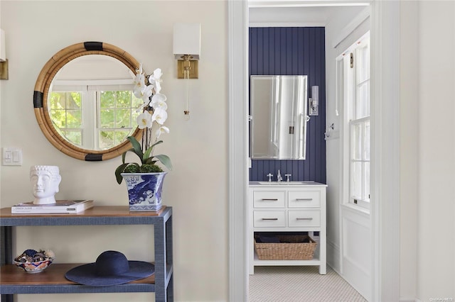 hall with a healthy amount of sunlight, light colored carpet, and sink