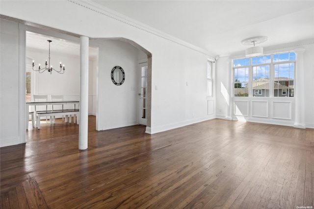 unfurnished living room with an inviting chandelier, dark wood-type flooring, and crown molding