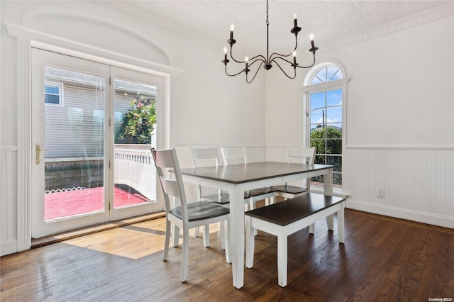 dining room with hardwood / wood-style flooring, an inviting chandelier, plenty of natural light, and wood walls