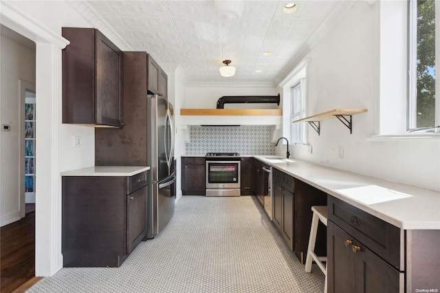 kitchen with sink, decorative backsplash, light wood-type flooring, appliances with stainless steel finishes, and dark brown cabinets