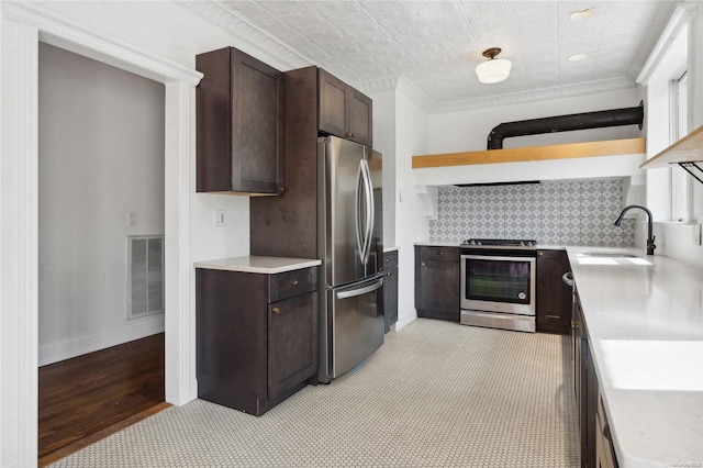 kitchen with sink, stainless steel appliances, light hardwood / wood-style floors, decorative backsplash, and dark brown cabinets