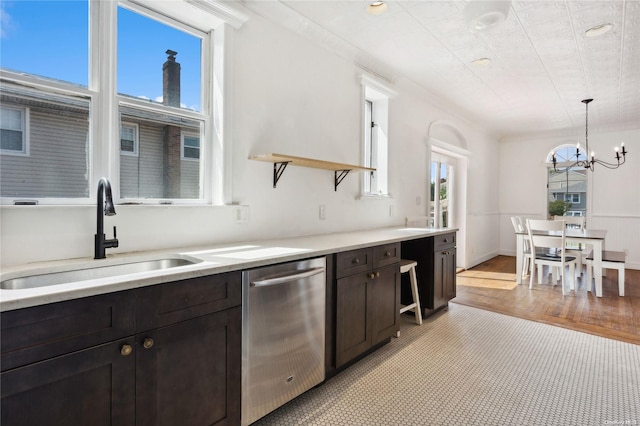 kitchen with dark brown cabinetry, sink, stainless steel dishwasher, and light wood-type flooring