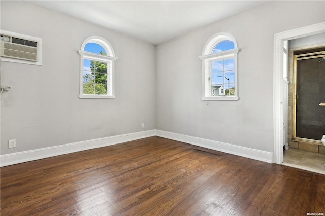 spare room featuring an AC wall unit and dark wood-type flooring