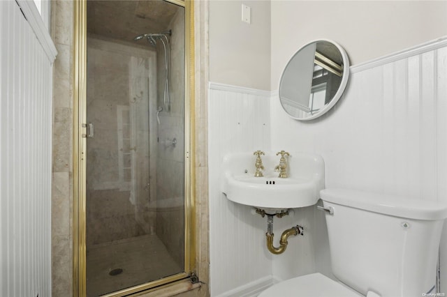 bathroom with toilet, a shower with shower door, and sink