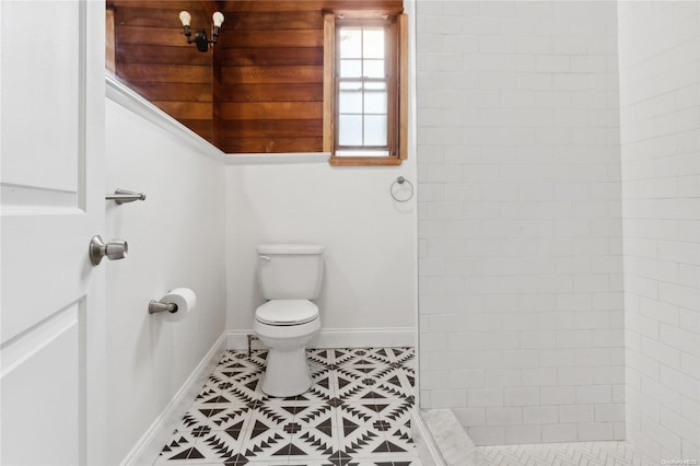 bathroom with a tile shower, tile patterned flooring, and toilet