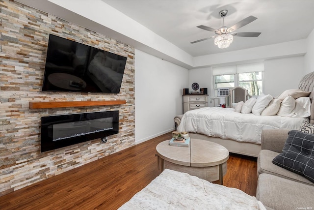 bedroom featuring a fireplace, ceiling fan, and dark hardwood / wood-style flooring