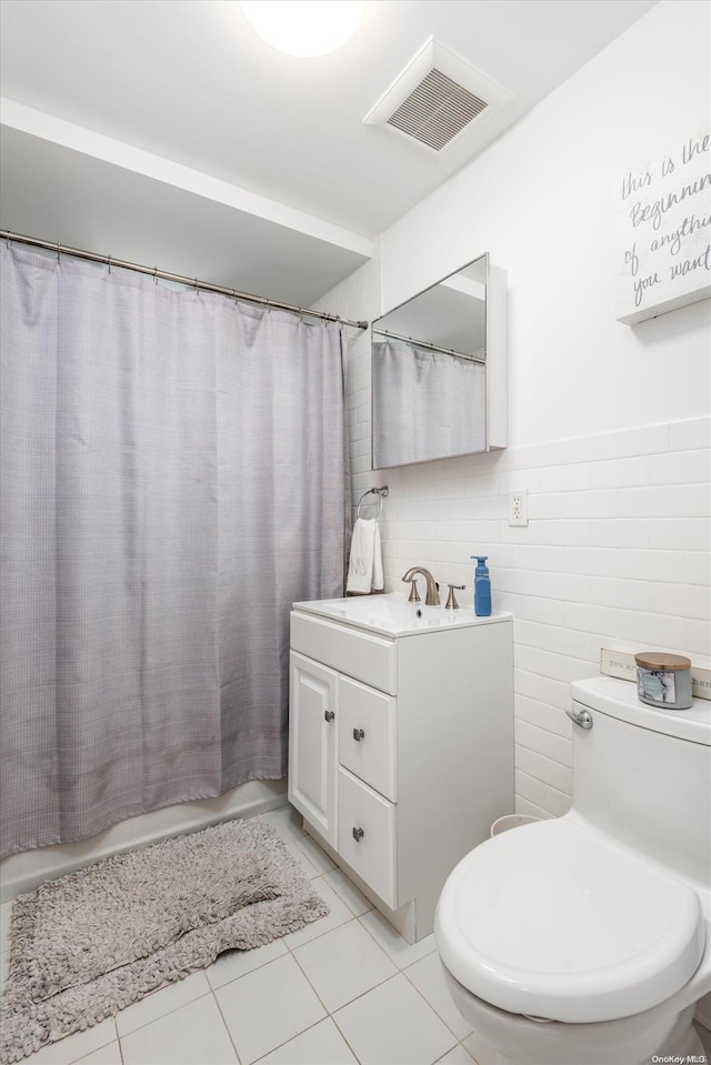 bathroom with tile patterned floors, vanity, toilet, and tile walls