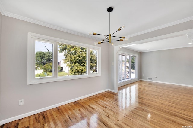 spare room with light wood-type flooring, an inviting chandelier, and ornamental molding