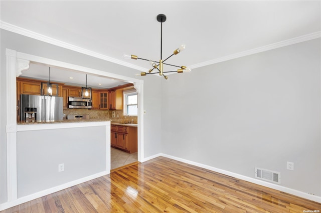 kitchen featuring kitchen peninsula, ornamental molding, light wood-type flooring, and appliances with stainless steel finishes