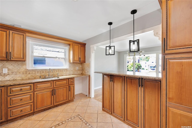 kitchen featuring decorative backsplash, light tile patterned floors, decorative light fixtures, and light stone counters