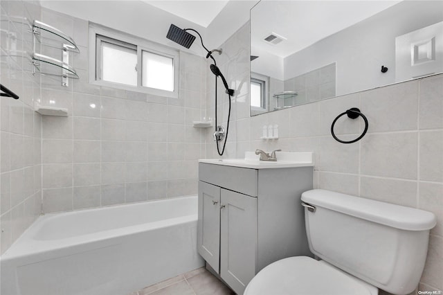 full bathroom featuring tile patterned flooring, toilet, vanity, tile walls, and tiled shower / bath