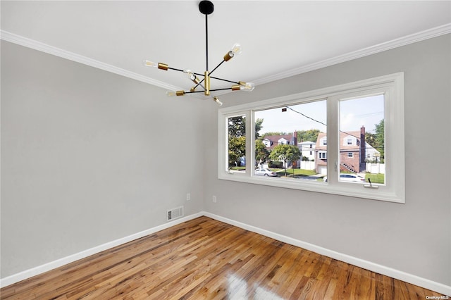 spare room with hardwood / wood-style flooring, crown molding, and a notable chandelier