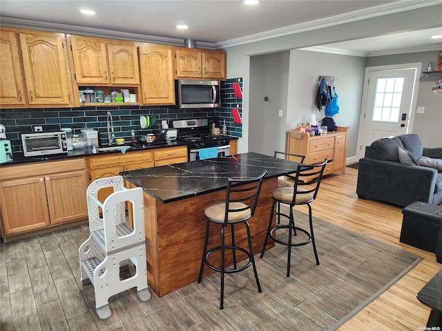 kitchen with a breakfast bar, a kitchen island, stainless steel appliances, and light hardwood / wood-style floors