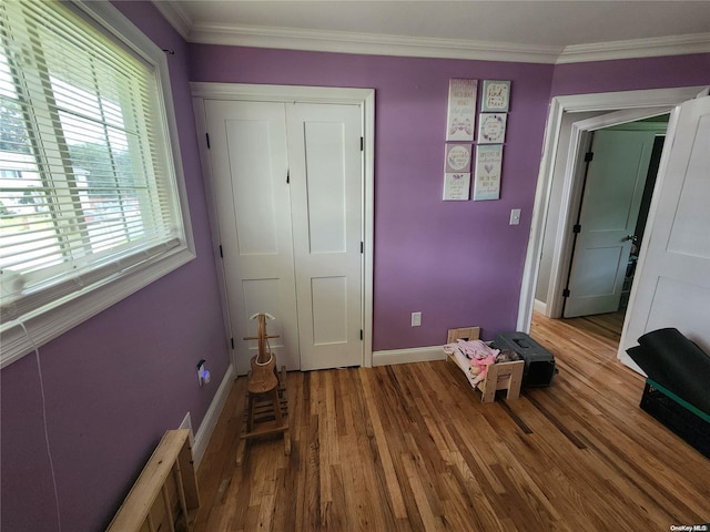 unfurnished bedroom featuring a closet, wood-type flooring, and ornamental molding