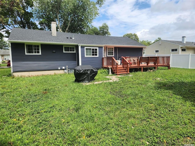 rear view of house featuring a wooden deck and a lawn