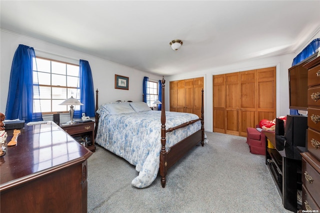 bedroom featuring light carpet and two closets