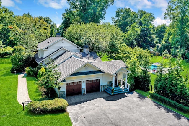 view of front of home featuring driveway, a front lawn, an attached garage, and stone siding