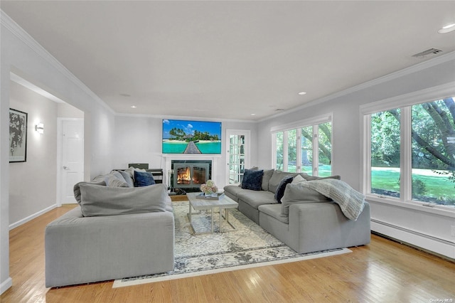 living room featuring a baseboard radiator, light wood-style flooring, visible vents, ornamental molding, and a glass covered fireplace