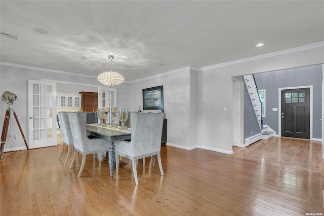 dining space with baseboard heating, wood finished floors, visible vents, and an inviting chandelier