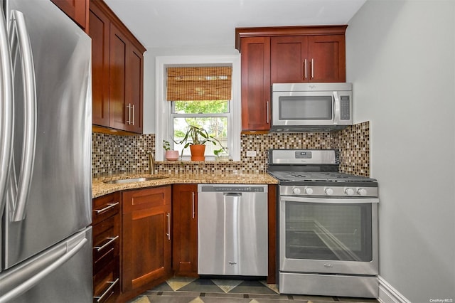 kitchen featuring tasteful backsplash, light stone countertops, sink, and appliances with stainless steel finishes