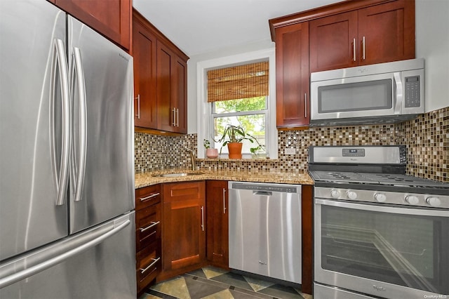 kitchen with backsplash, light stone counters, sink, and stainless steel appliances