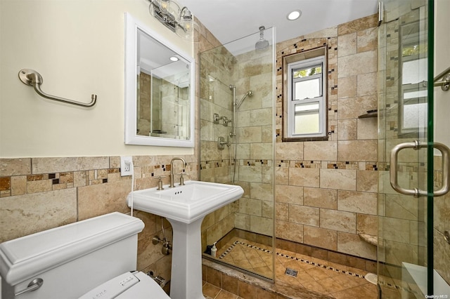 bathroom featuring sink, an enclosed shower, tile walls, and toilet