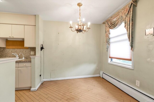 unfurnished dining area featuring baseboard heating, sink, light wood-type flooring, and an inviting chandelier